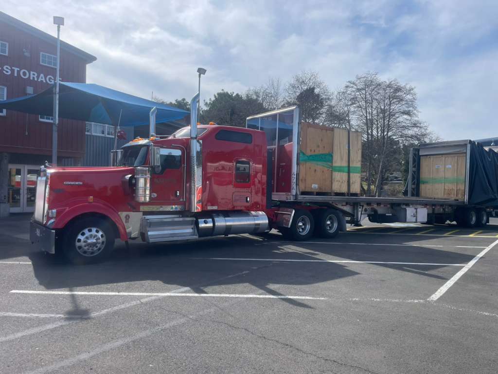 Koval Trucking red truck hauling protected Conestoga freight